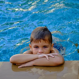 Kleiner Junge mit roten Augen am Schwimmbeckenrand