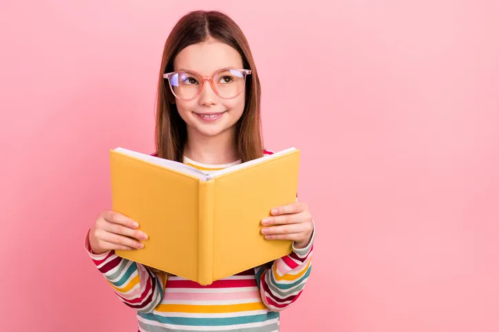 Schulmäden mit Brille und Buch in der Hand