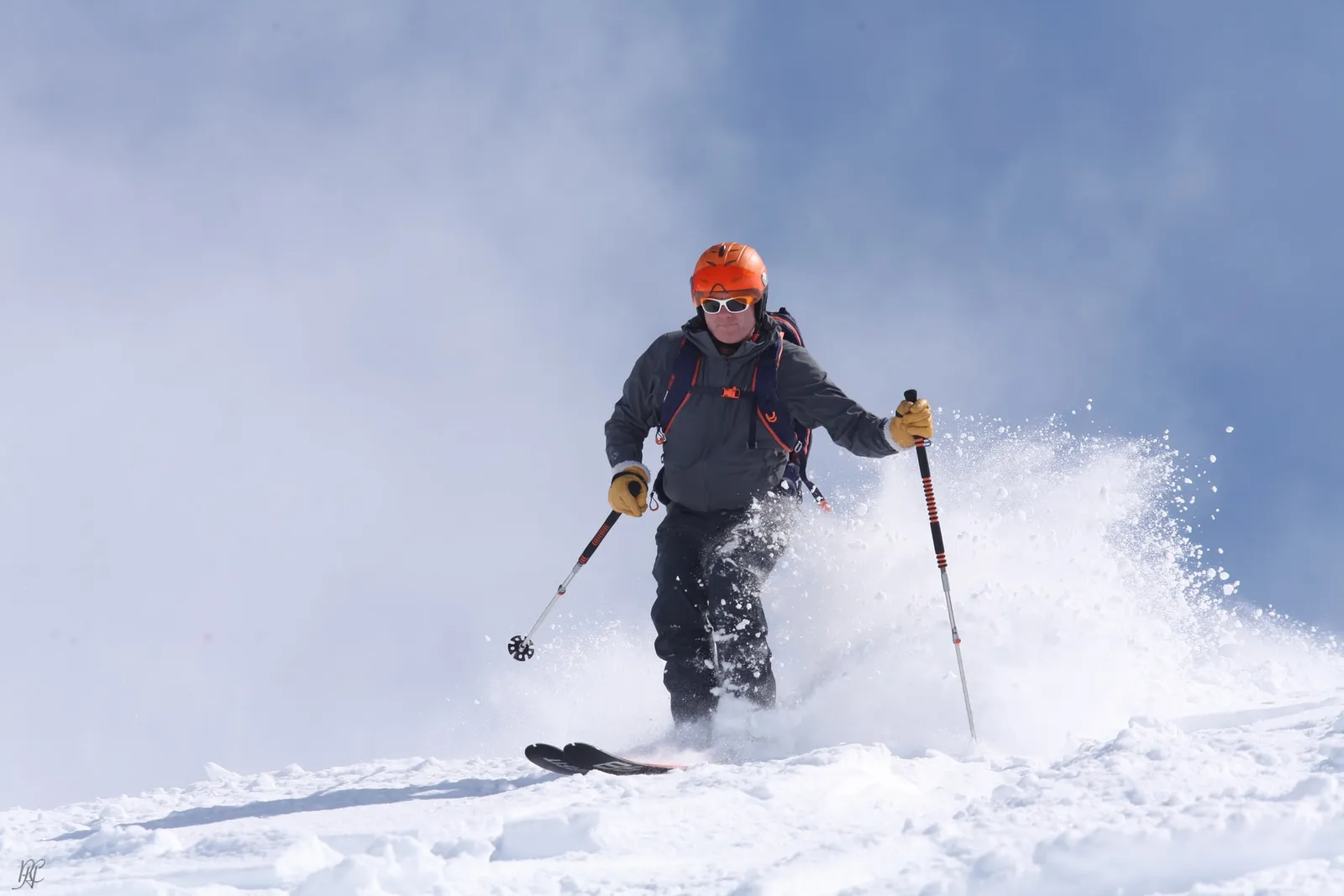 Skifahrer in Schneewolke vor blauem Himmel