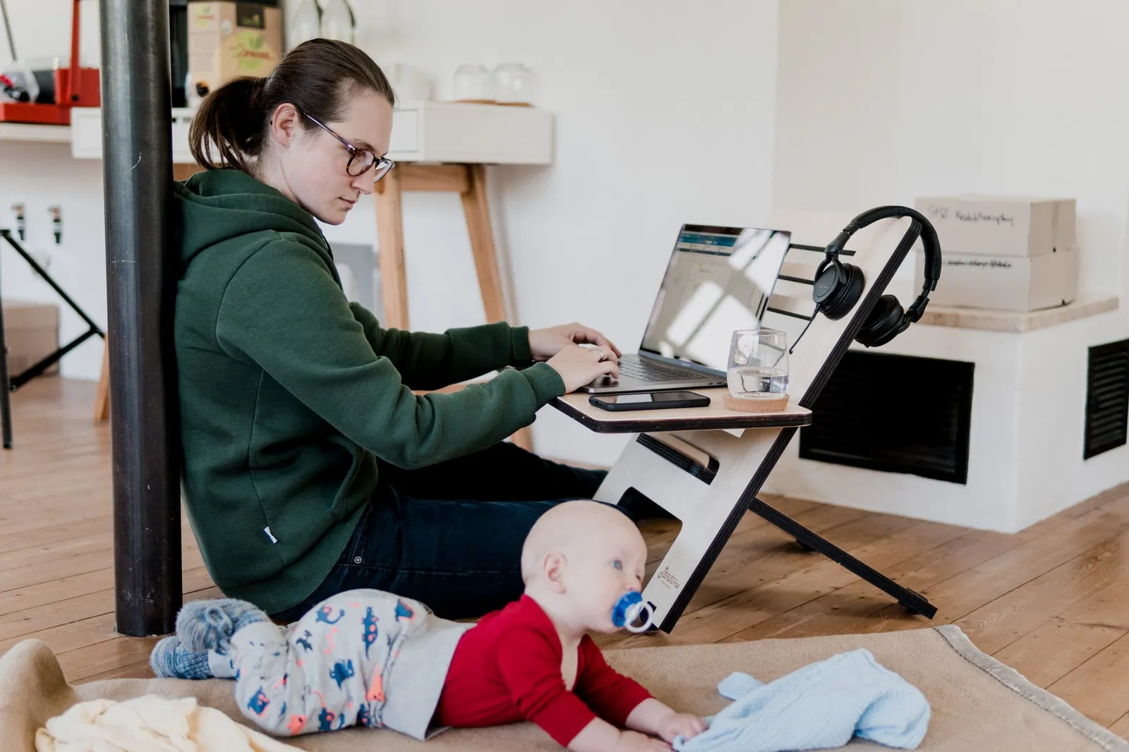Frau sitzt auf dem Boden mit Computer und Baby.