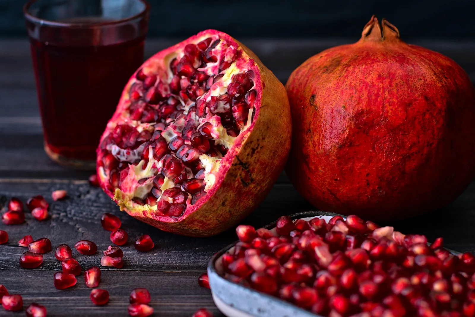 Ein halber aufgeschnittener Granatapfel hinter einer Schüssel mit ausgelösten Kernen