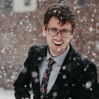 Junger Mann im Anzug mit Brille bei Schneefall