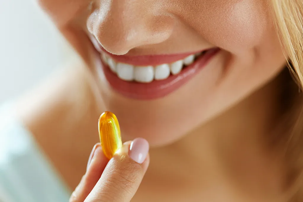 Close Up junge hübsche Frau nimmt eine Omega-3- Kapsel
