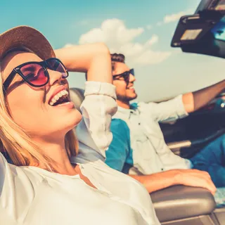 Glückliche junge Frau auf dem Beifahrersitz im Cabrio