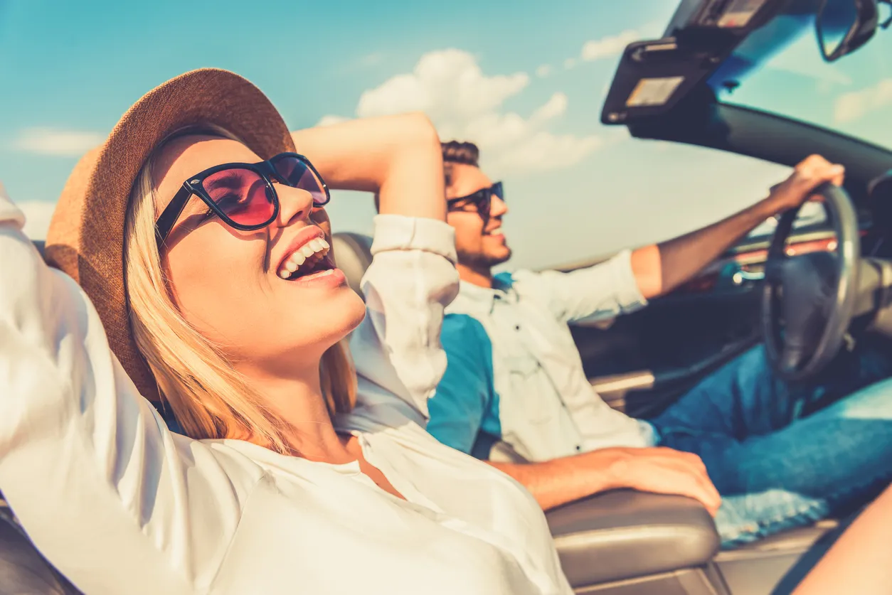 Glückliche junge Frau auf dem Beifahrersitz im Cabrio