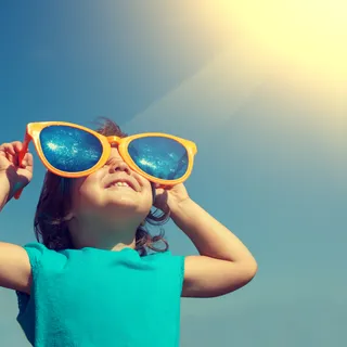 Kleines Knd schaut mir einer Riesensonnenbrille in den Himmel