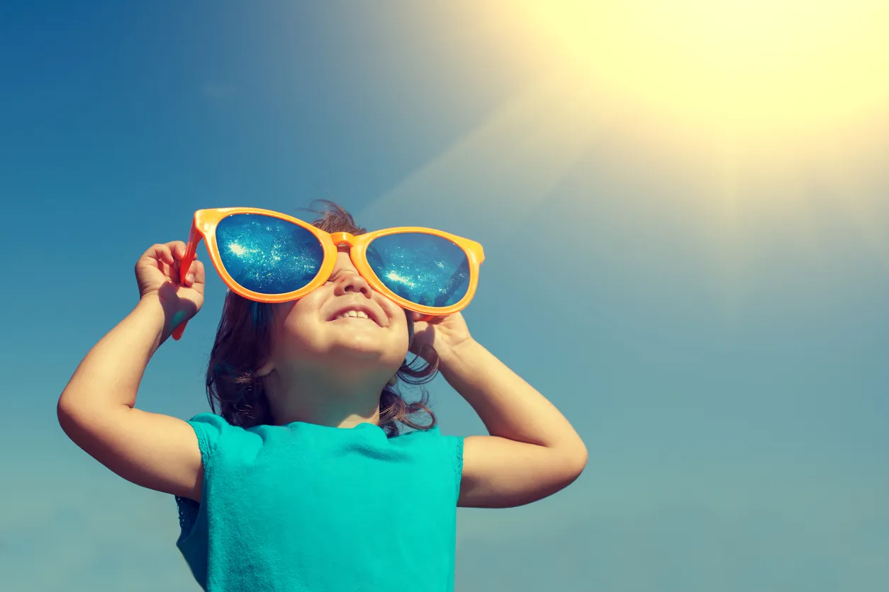 Kleines Knd schaut mir einer Riesensonnenbrille in den Himmel