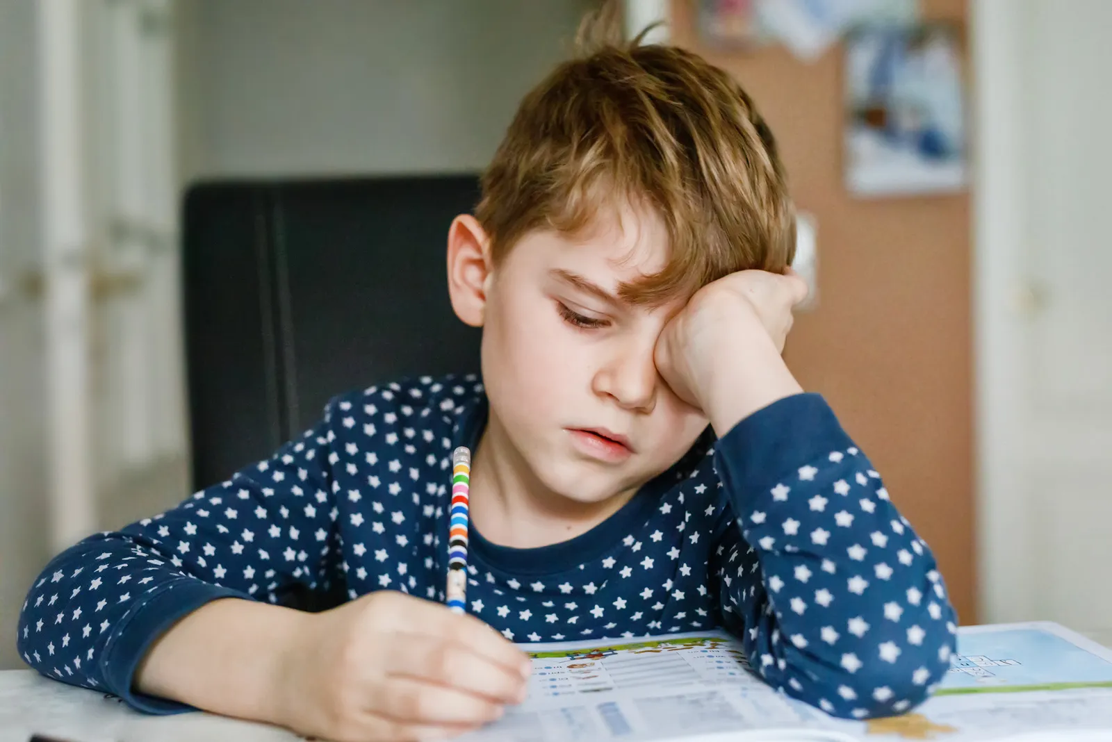 Schuljunge sitzt motivationslos über Schulheft
