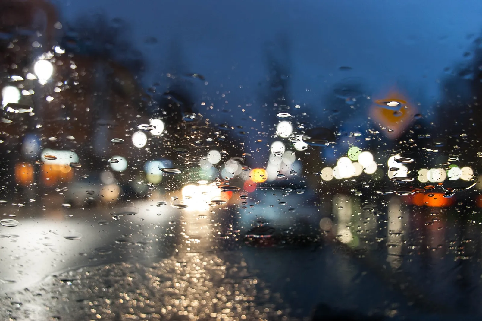 Verschwommen Lichter vor einer regennassen Windschutzscheibe bei Nacht