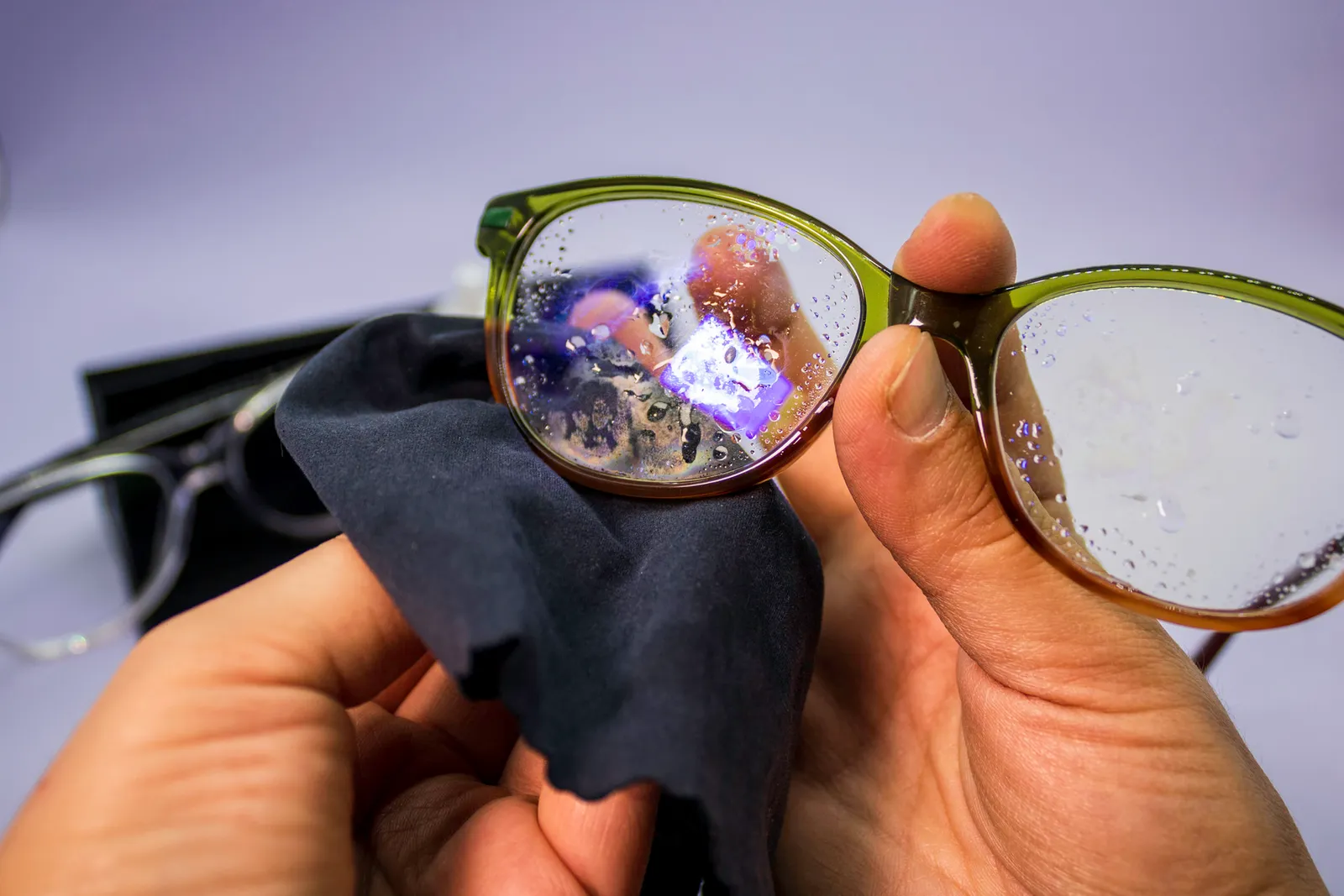 Nahaufnahme feuchte Brille, die mit einem Mikrofasertuch geputzt wird